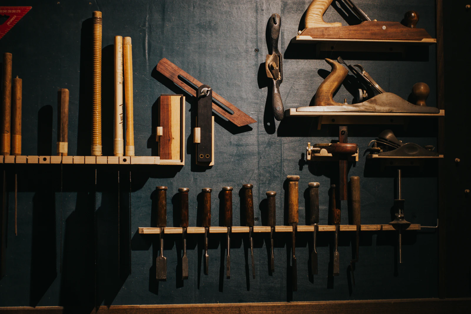 Woodworking chisels and planes arranged on a dark wall