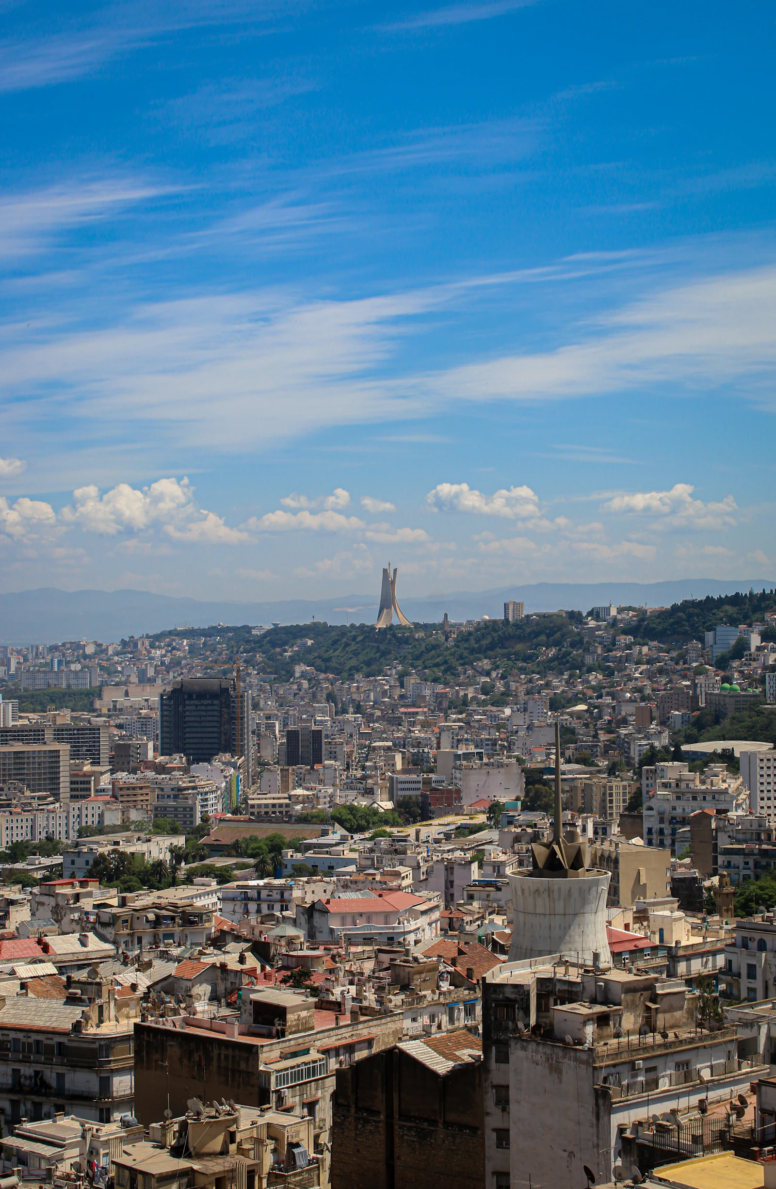 Panorama of Algiers under a blue sky, with the Martyrs’ Memorial on the hill in the distance