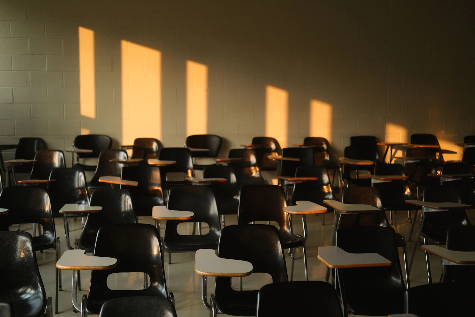 An empty classroom with afternoon sunlight casting shadows across the desks
