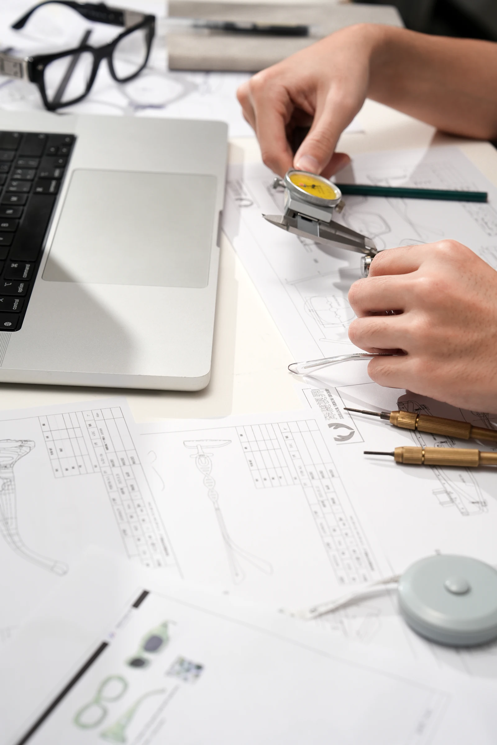 A person measuring a technical drawing with a dial caliper