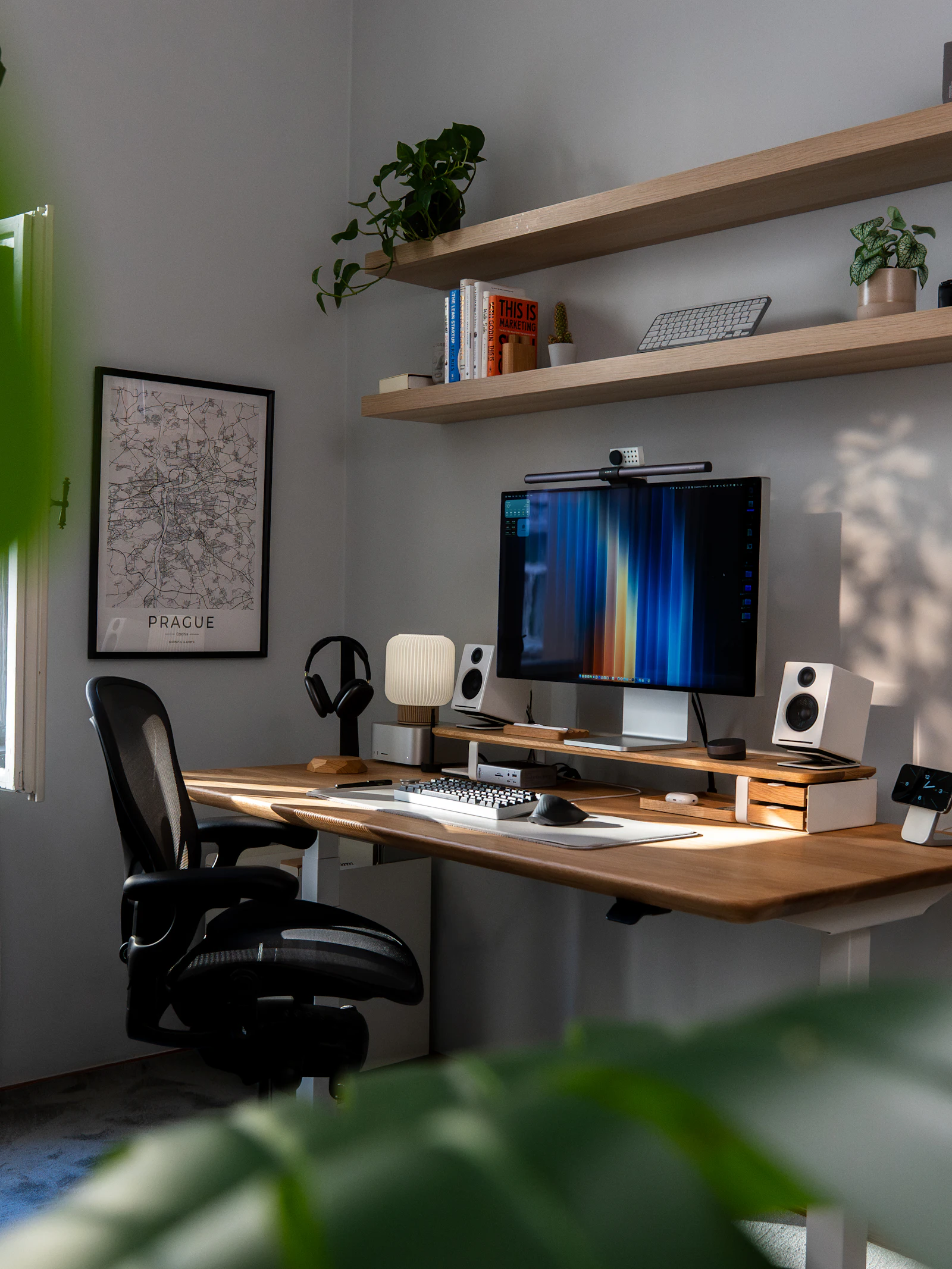 A tidy home office with a large monitor, speakers and shelves